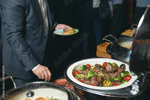 Catering buffet food indoor in luxury restaurant with meat colorful fruits and vegetables. People at a banquet taking different food. Colleagues Buffet Party Brunch Dinning Concept