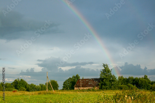 Rainbow Above Wheat Field. Sideward Ripe Crop Field After Rain and Colorfull Rainbow in Background Rural Countryside.