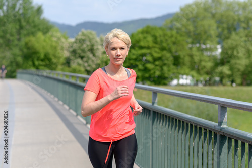 Sporty woman jogging across a pedestrian bridge © michaelheim