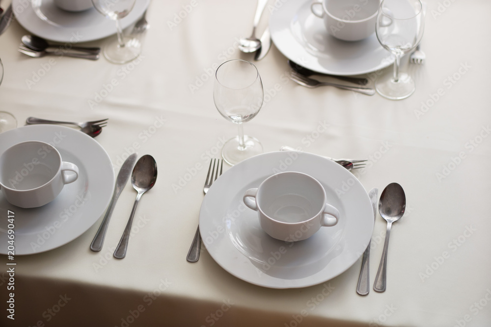 Tableware before the family party. Cutlery and plates on the table with a tablecloth. Tableware before the family party. Cutlery and plates on the table with a tablecloth.