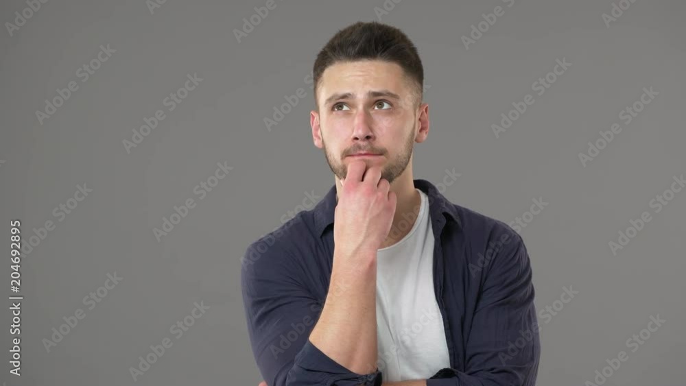 Portrait of good-looking guy in casual clothing posing with doubting look while thinking or weighing pros and cons, isolated over gray background. Concept of emotions Portrait of good-looking guy in casual clothing posing with doubting look while thinking or weighing pros and cons, isolated over gray background. Concept of emotions