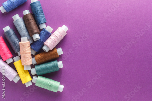Colorful sewing threads on violet background