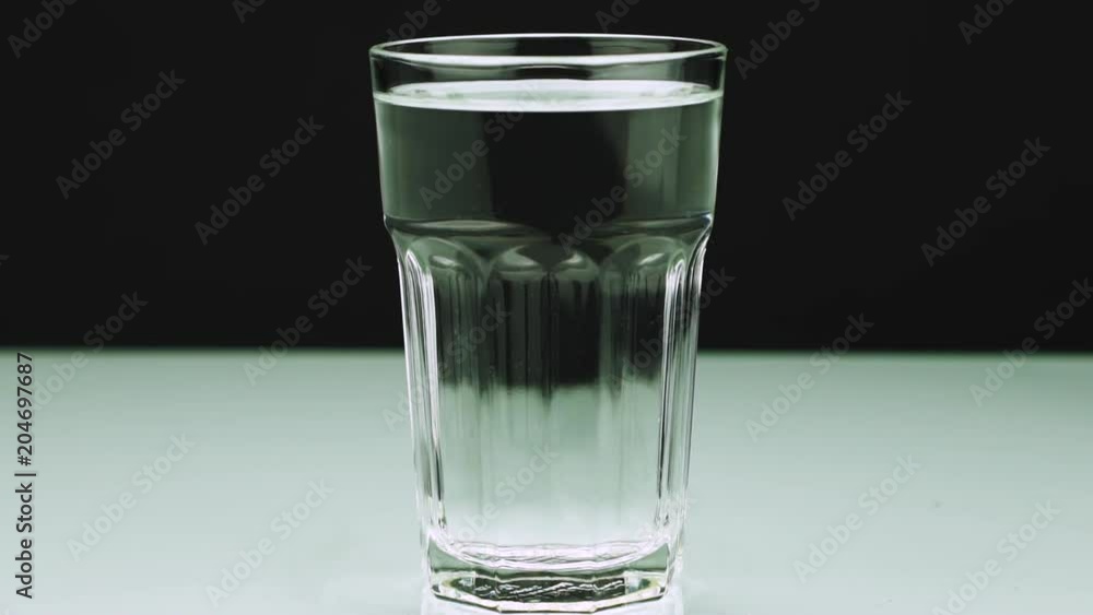An effervescent pill against pain falls into a glass and dissolves Close-up slow-motion shot of aspirin on a colored background An effervescent pill against pain falls into a glass and dissolves Close-up slow-motion shot of aspirin on a colored background