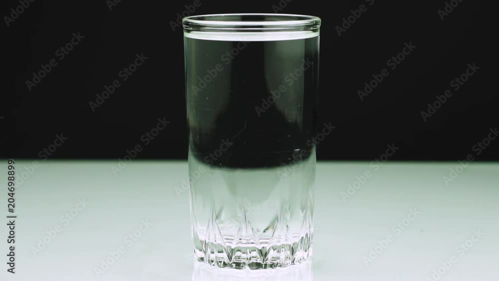 An effervescent tablet against pain falls into a glass and dissolves Close-up slow-motion shot of aspirin on a blackbackground An effervescent tablet against pain falls into a glass and dissolves Close-up slow-motion shot of aspirin on a blackbackground
