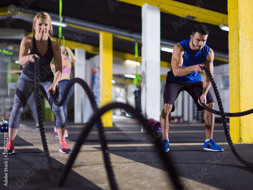 sports couple doing battle ropes crossfitness exercise