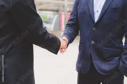 attractive business man shaking hand for complete deal together business successful at outdoor in city. teamwork concept. partnership concept and dealership concept.
