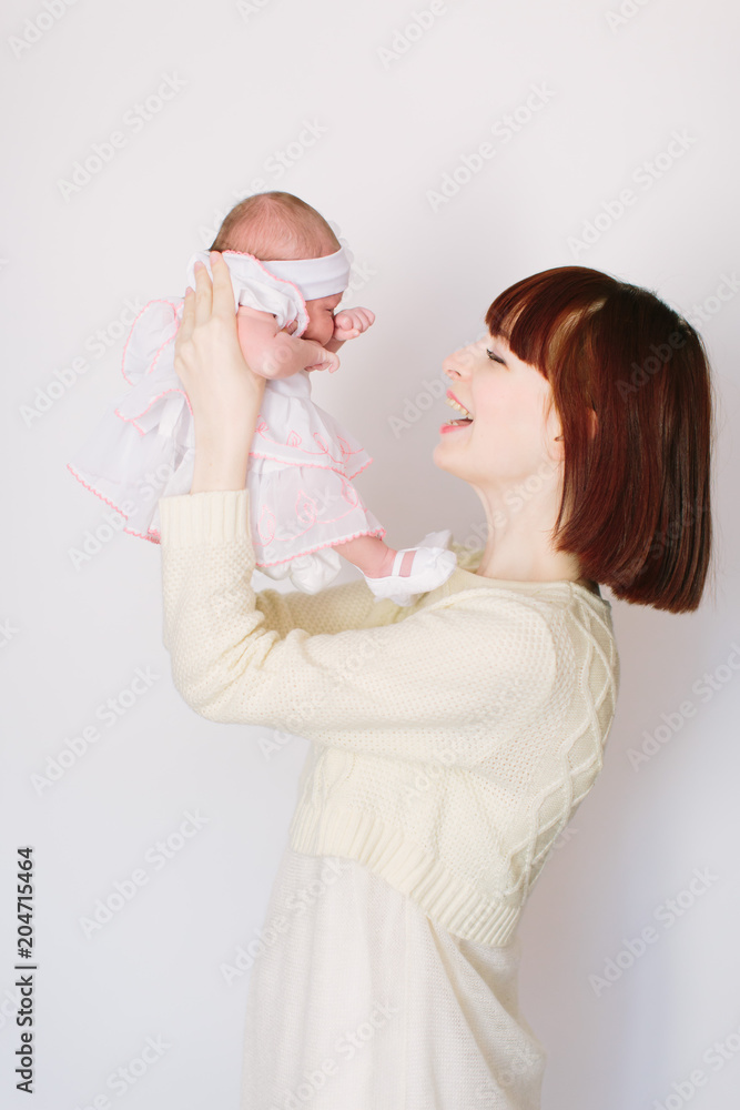 Happy family: beautiful young mother in white clothes and her baby girl playing isolated on white background Happy family: beautiful young mother in white clothes and her baby girl playing isolated on white background