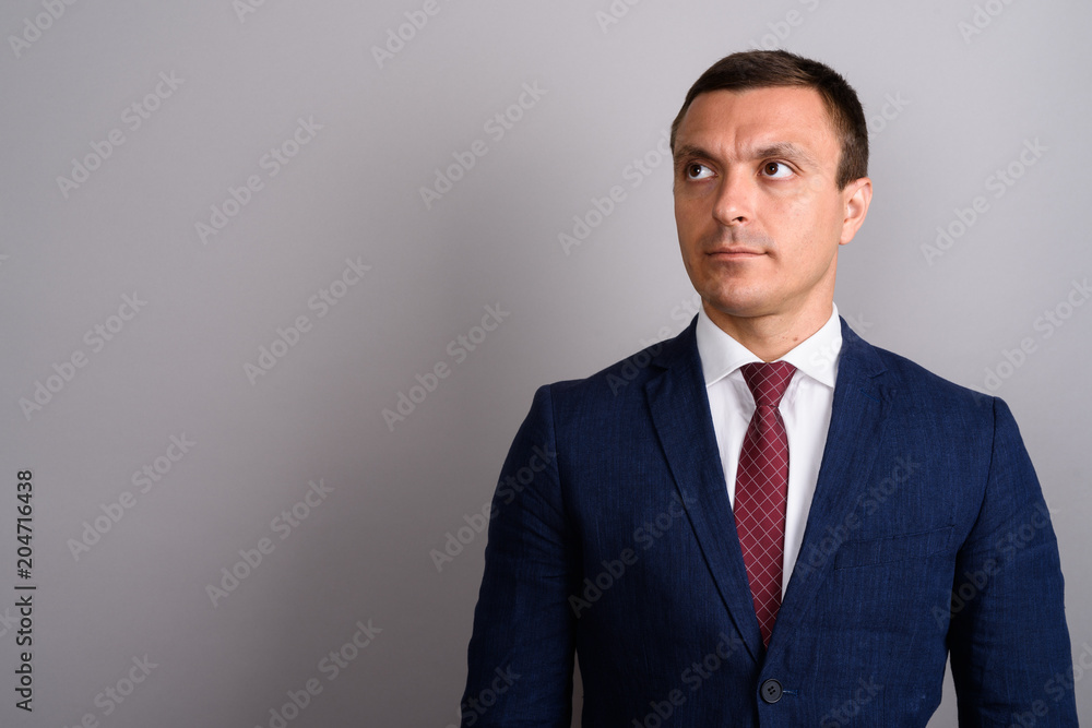 Businessman wearing suit against gray background Businessman wearing suit against gray background