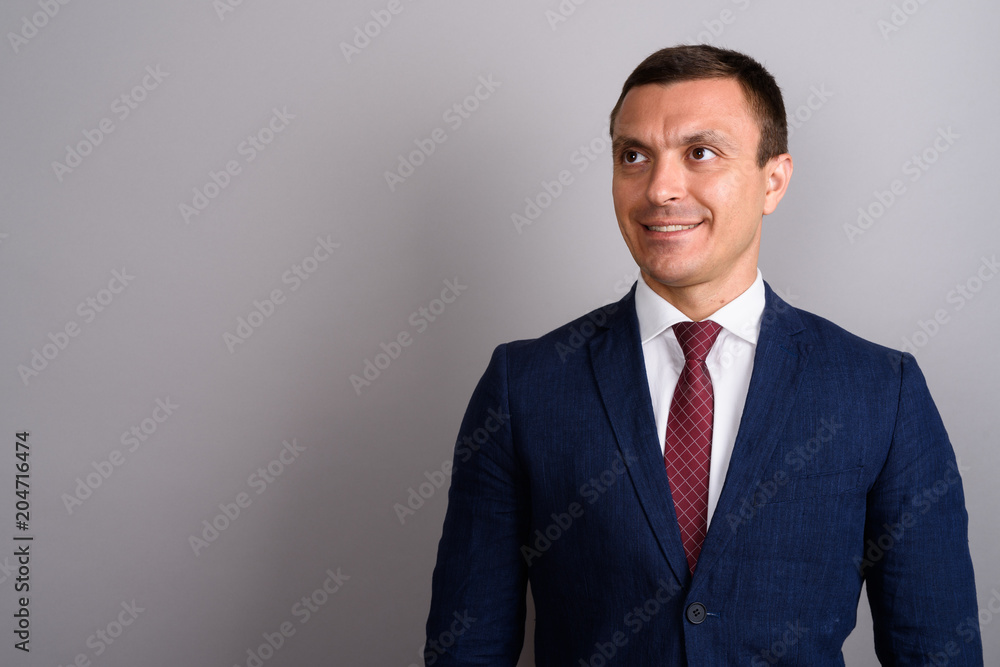 Businessman wearing suit against gray background Businessman wearing suit against gray background