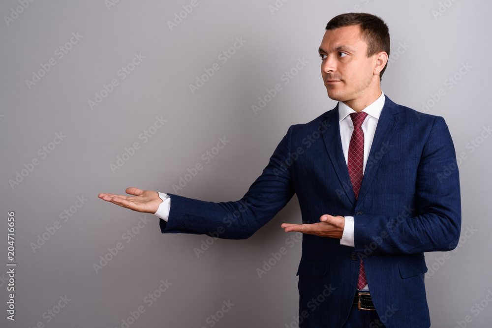 Businessman wearing suit against gray background Businessman wearing suit against gray background