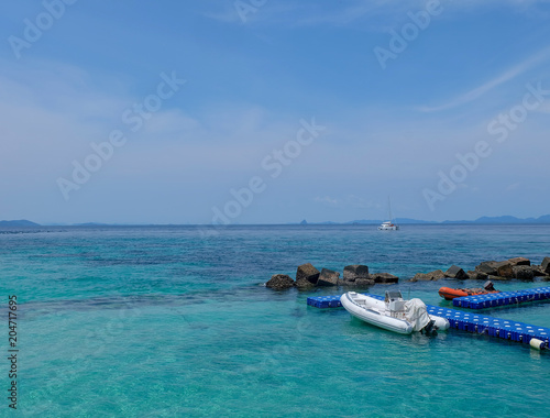Beautiful sea  crystal clear water. White Inflatable Lifeboat with small motor in the sea. There are many stone here near the coast at the island in Thailand.