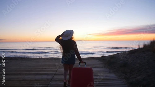 Young woman with a suitcase on the sunny beach photo