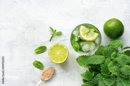 Mojito cocktail (Caipirinha) on white concrete table. Top view. Copy space. Cold drink with lime, ice and rum. 