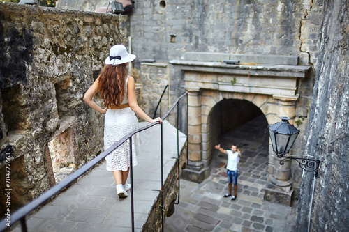 the girl in white dress and hat on the balcony looks down at the guy asking for forgiveness or singing serenade for confessing in love