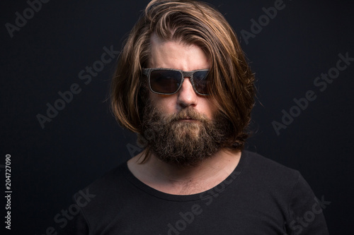 Portrait of cool serious man wearing sun glasses isolated on black