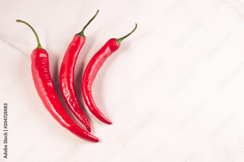 red Chile on white background/three red Chile on white stone background. Top view. Copy space red Chile on white background/three red Chile on white stone background. Top view. Copy space