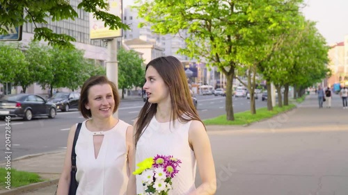 Mother and adult daughter laughing and chatting in the park on a sunny day photo