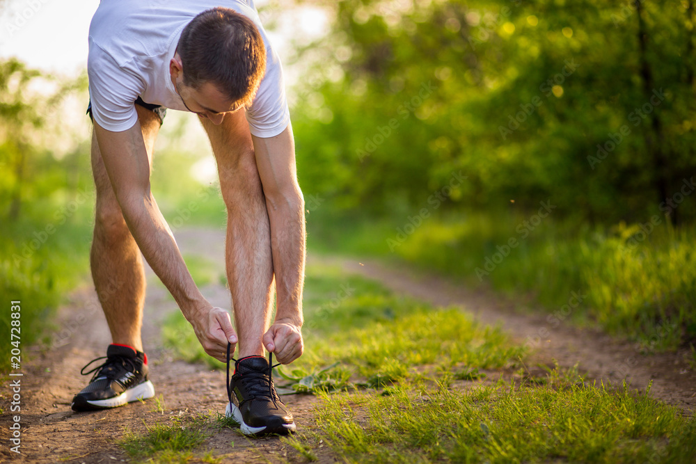 Man tying running shoes. Healthy lifestyle. Athlete tying laces for jogging  on road in barefoot running shoes. Runner getting ready for training Stock  Photo | Adobe Stock