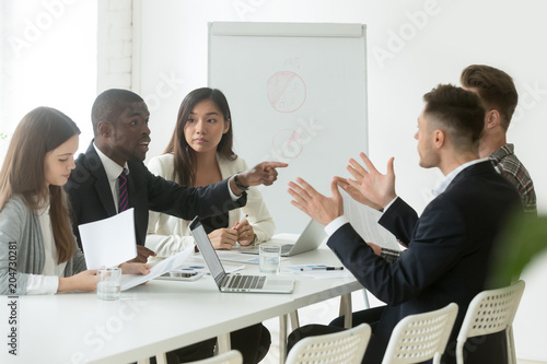 Diverse employees arguing during team meeting, african office worker disagreeing with caucasian colleague, black and white businessmen disputing at negotiations, multiracial conflict at work concept photo