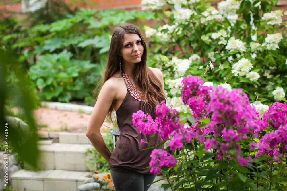 close-up Outdoor Portrait Of Beautiful Pretty Woman In Spring Garden. Magic beautiful brunette woman with a wreath of white fresh flowers in a blooming garden. portrait of happy smiling girl.