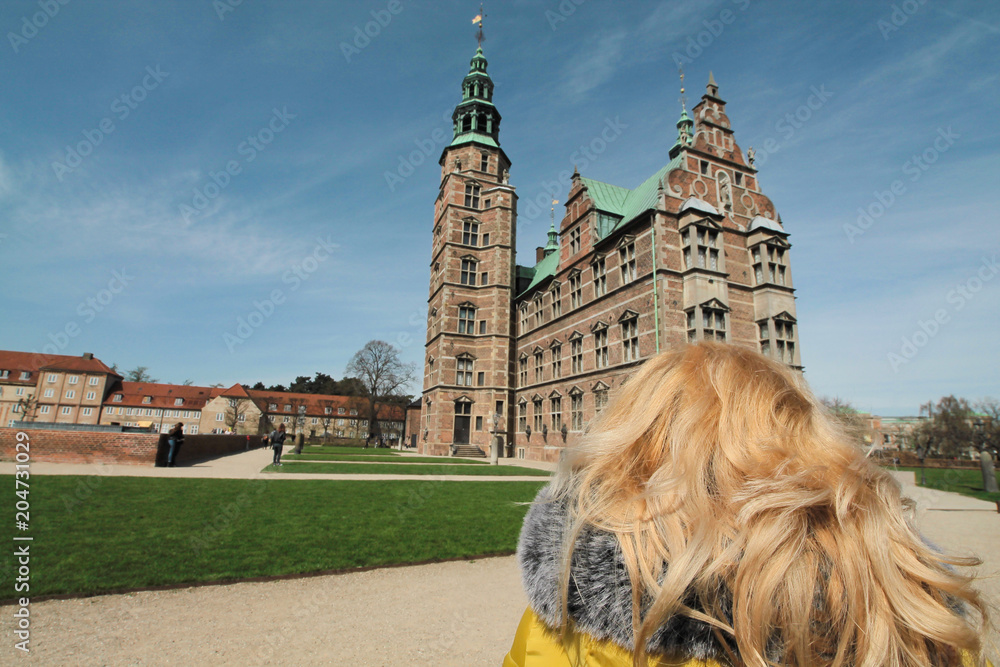 Obraz premium Primo piano di una ragazza dai capelli biondi rivolta verso il castello di Rosenborg in Copenhagen