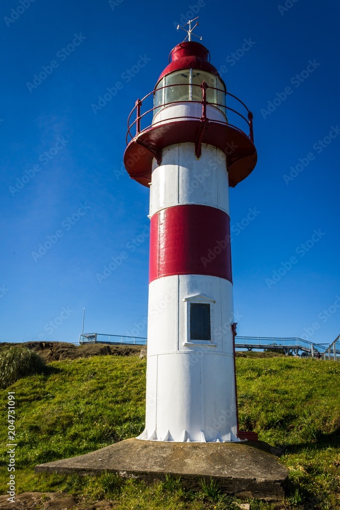 Red and white lighthouse on Niebla Fort on sunny day in South Chile