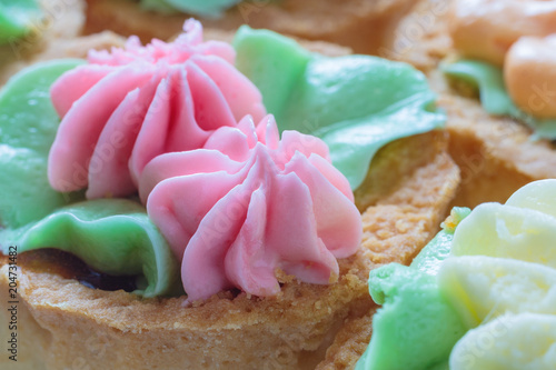Close up view of a shortbread cake with pink cream in the shape of flowers on top (shallow depth of field)