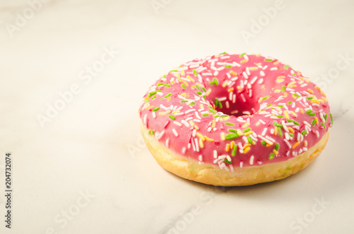 Sweet and colourful pink doughnut/Sweet and colourful pink doughnut on a marble background. Selective focus and copyspace