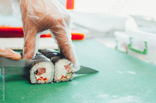 professional chef, chef the process of making sushi rolls, spins bamboo Mat and cut slices photo