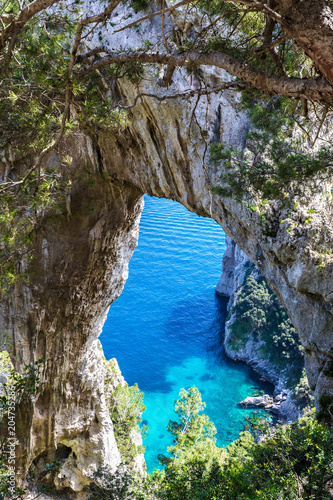 Capri, Italy. Capri Island in a beautiful summer day, with faraglioni rocks and natural stone arch. Close up of the natural rocky arc.