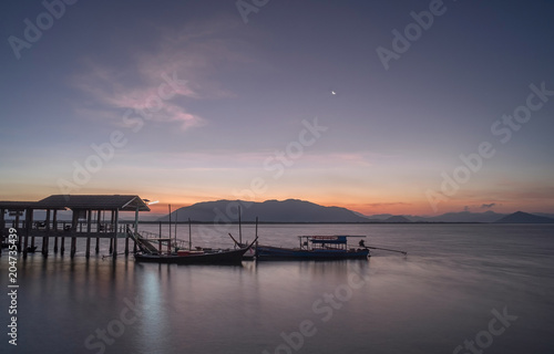 Early morning when the sun rises. With a boat waiting for passengers across the island. subject is blurred and noise. © Wuttichai