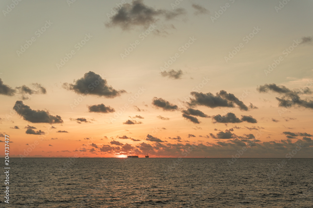 Sunset at sea. Offshore oil and gas industry, sea oil production and storage on background.