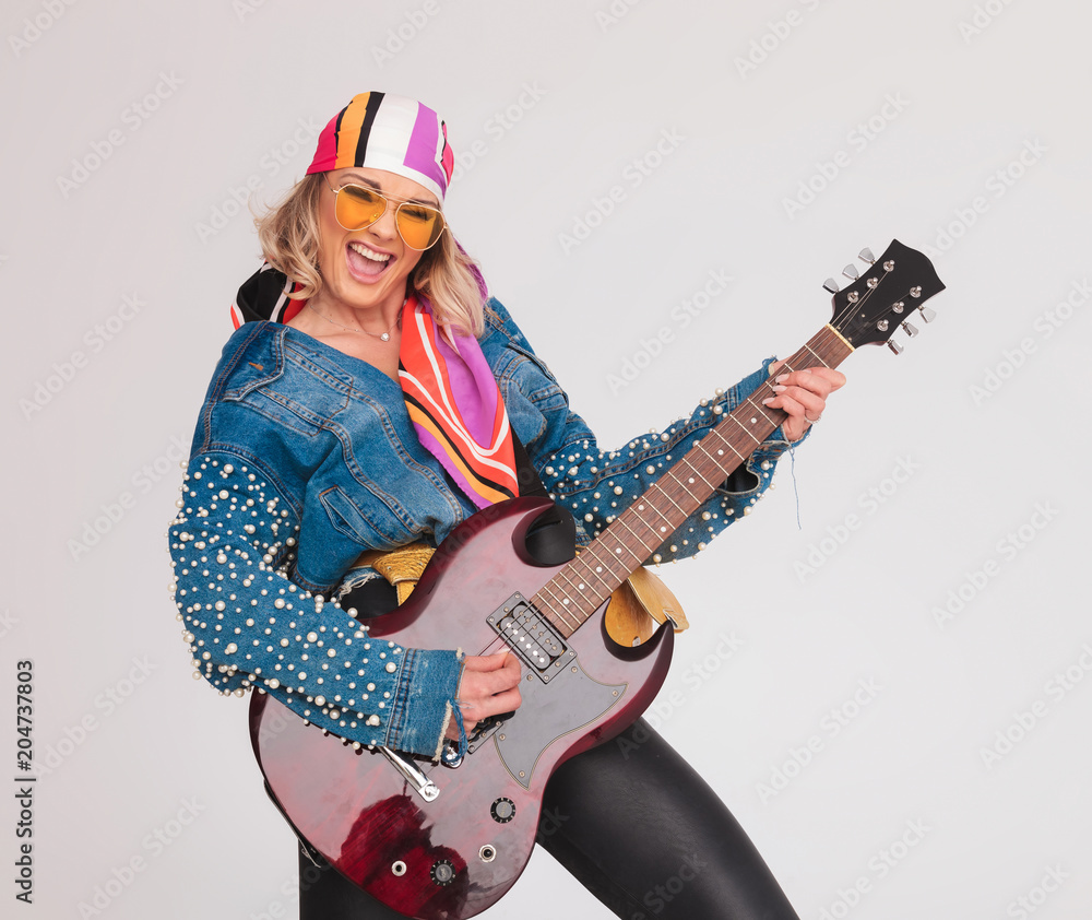 joyful woman with colorful outfit enjoys playing the electric guitar joyful woman with colorful outfit enjoys playing the electric guitar