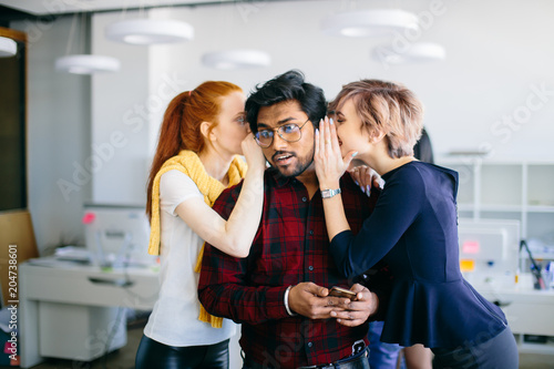 closeup portrait of ginger and fair-haired women telling secrets to their Hindu colleague. backstage collusion. intrigue at work