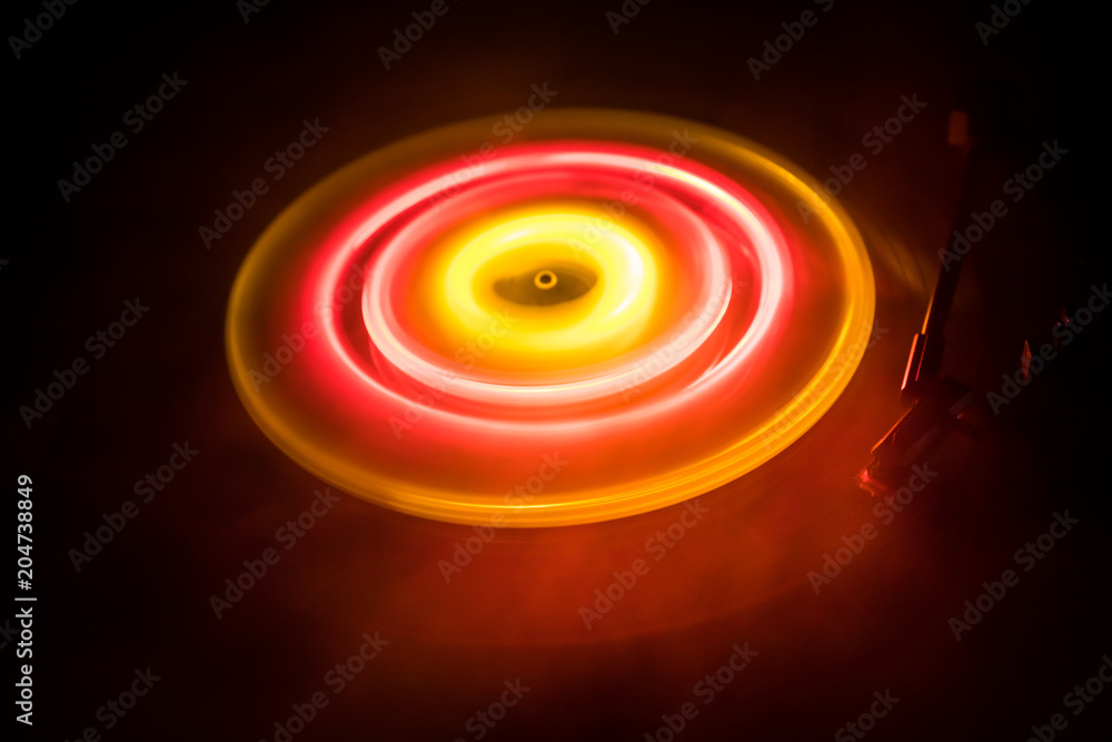 Turntable playing vinyl with glowing abstract lines concept on dark background Turntable playing vinyl with glowing abstract lines concept on dark background