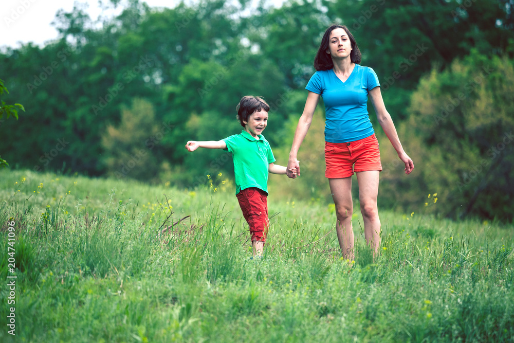 Fototapeta premium The boy walks with his mother in the meadow.