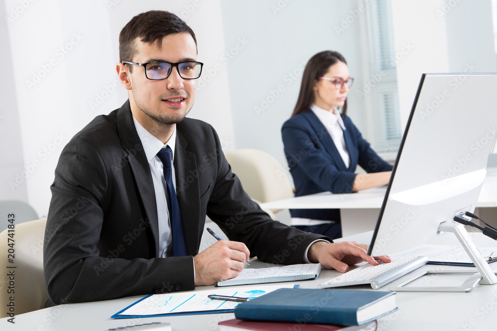 Young businessman working with computer in an office Young businessman working with computer in an office