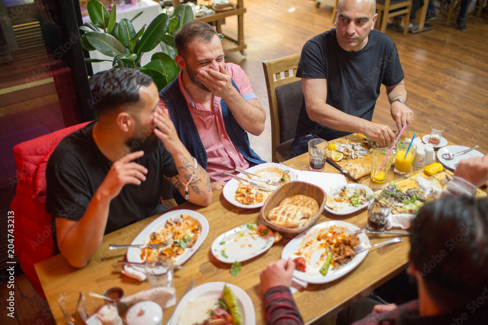 Group of people in restaurant enjoying Middle Eastern food. Selective focus