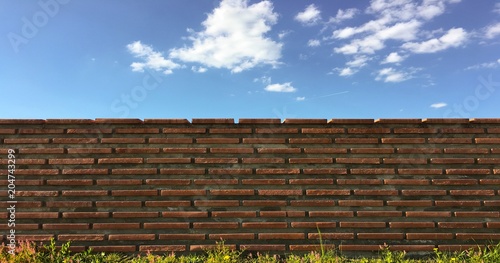 Tableau sur toile brick wall with white clouds in blue sky