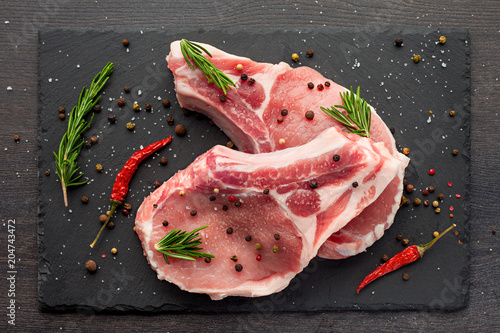 Canvas Print fresh raw meat with spices and rosemary and red pepper on black slate, on dark b