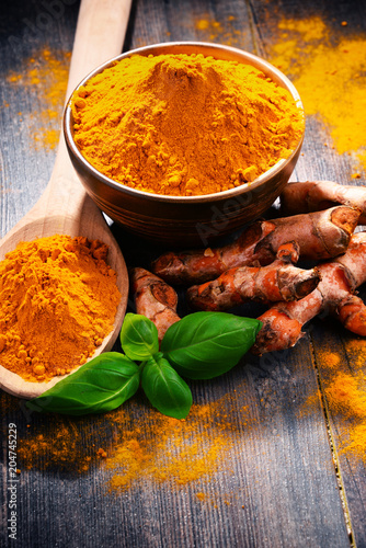 Composition with bowl of turmeric powder on wooden table