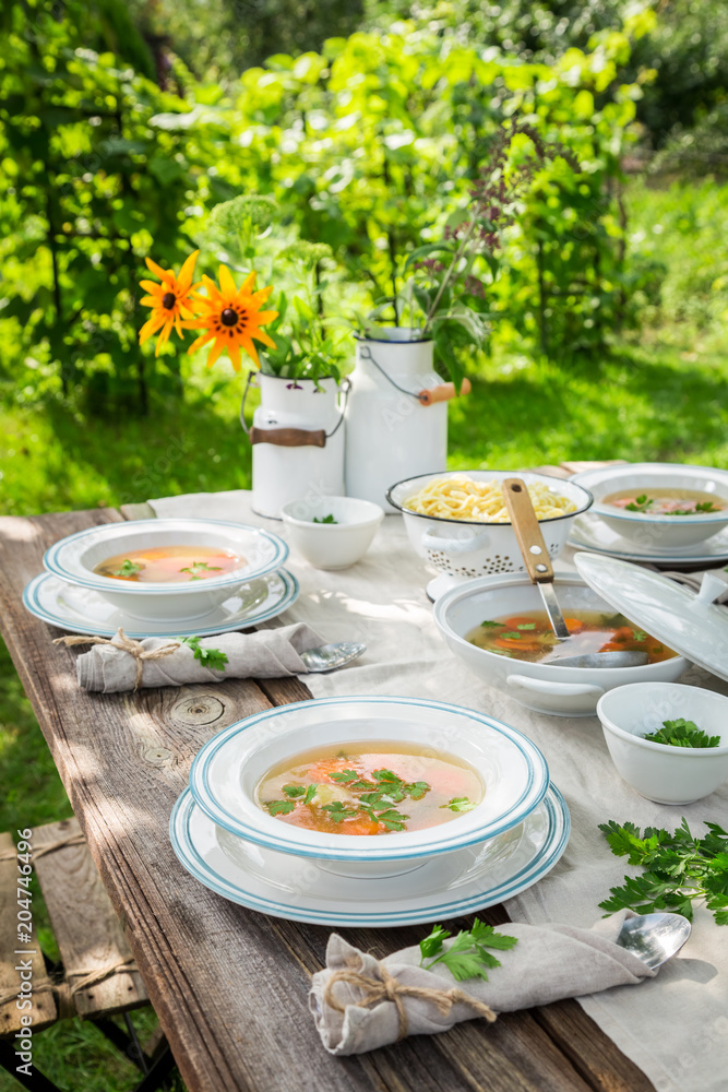 Fototapeta Homemade chicken soup with fresh vegetables in summer garden