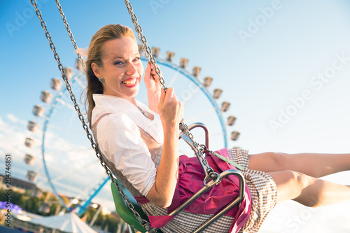 young sexy woman is doing oktoberfest in munic summer, spring folk festival she is wearing a dirndl and holding a hear brezn in her hand