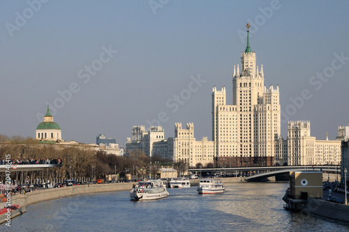 Moscow vessels / Passenger vessels are floating on Moscow River with a Stalin skyscraper in the background, Moscow, Russia