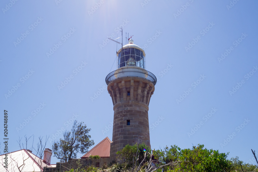 Barenjoey Lighthouse on a clear blue sky with sun rays shining from above