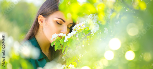 Beauty young woman enjoying nature in spring apple orchard, Happy beautiful girl in a garden with blooming fruit trees