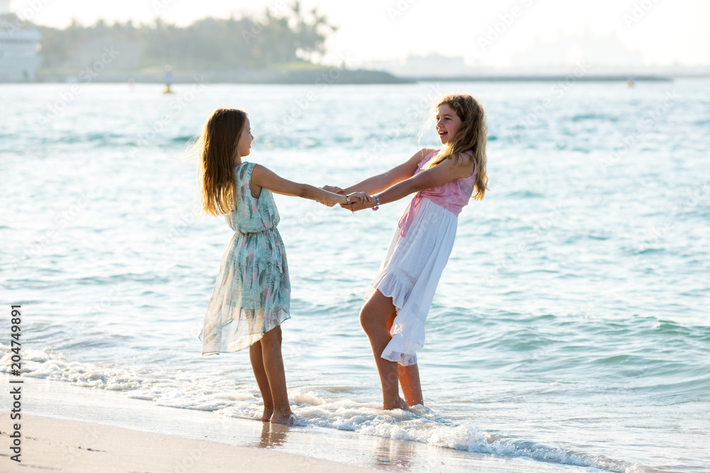 Two teenager girls dancing on the beach