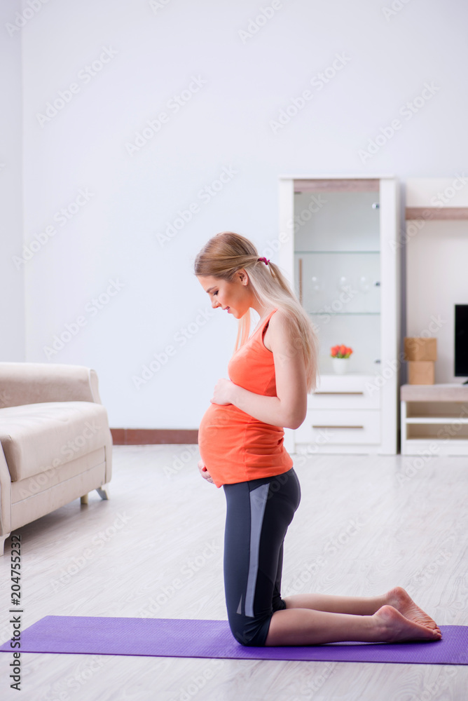 Pregnant woman doing sport exercise at home