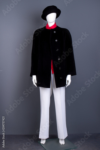 Black hat, coat and white women trousers. Mannequin dressed in black women topcoat and white pants. Female fashion outerwear.