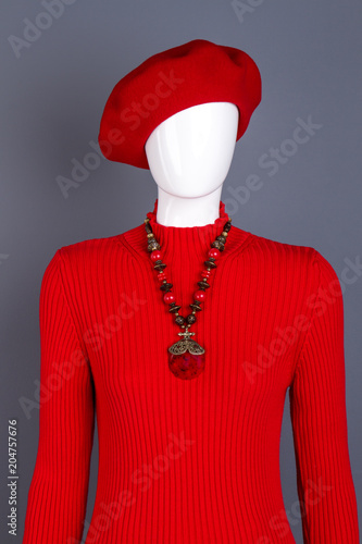Red beret and pullover on mannequin. Red turtleneck sweater and necklace. Women clothes and accessories.